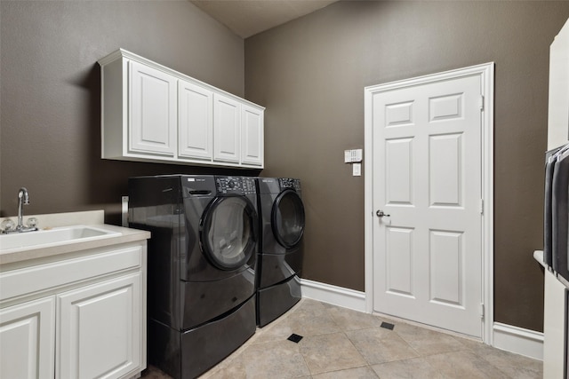 clothes washing area featuring cabinet space, a sink, tile patterned floors, baseboards, and washer and clothes dryer