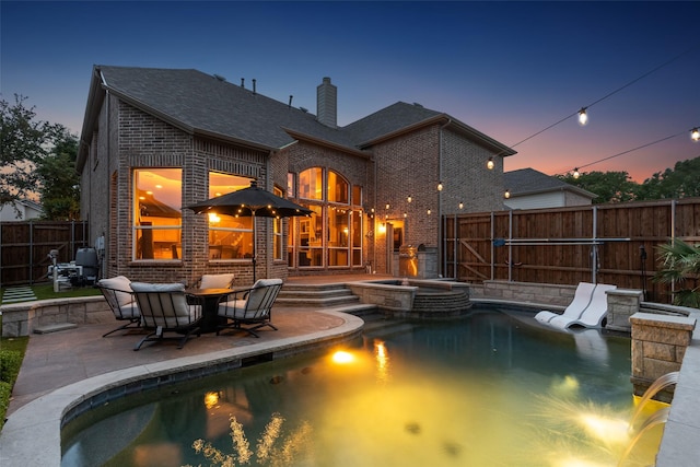 view of swimming pool with a patio, a pool with connected hot tub, and a fenced backyard
