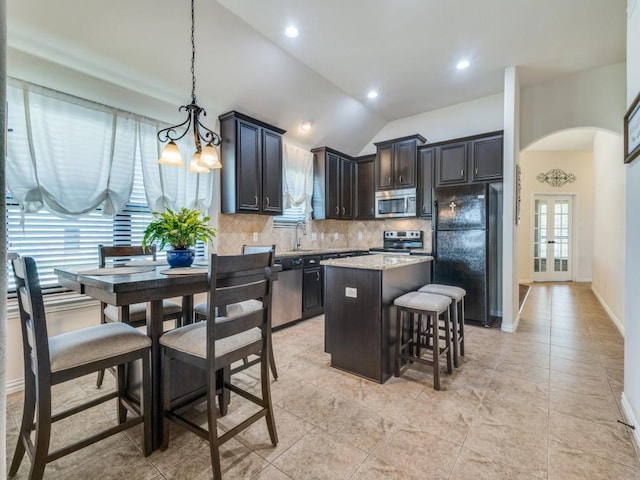 kitchen featuring decorative backsplash, a kitchen island, a kitchen bar, arched walkways, and stainless steel appliances