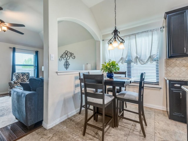 dining room with baseboards, lofted ceiling, and ceiling fan with notable chandelier