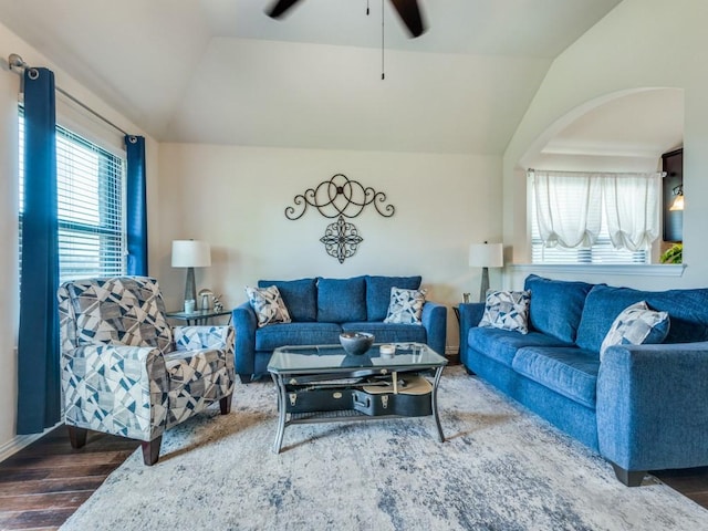 living room with a ceiling fan, arched walkways, wood finished floors, and vaulted ceiling