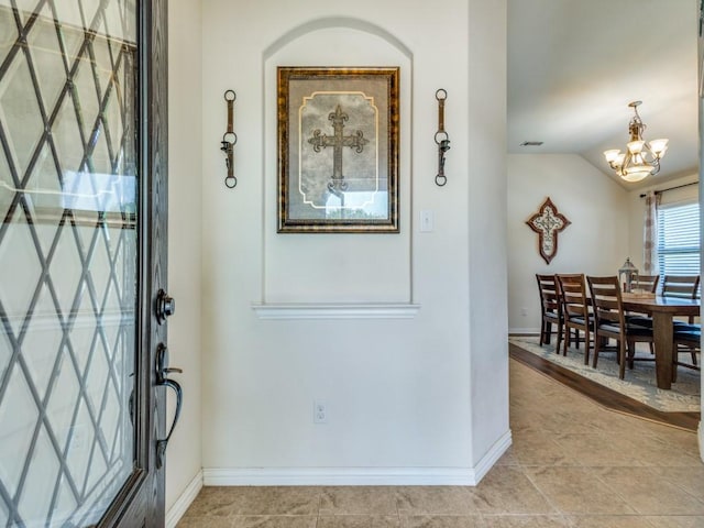 entrance foyer featuring an inviting chandelier, baseboards, and lofted ceiling