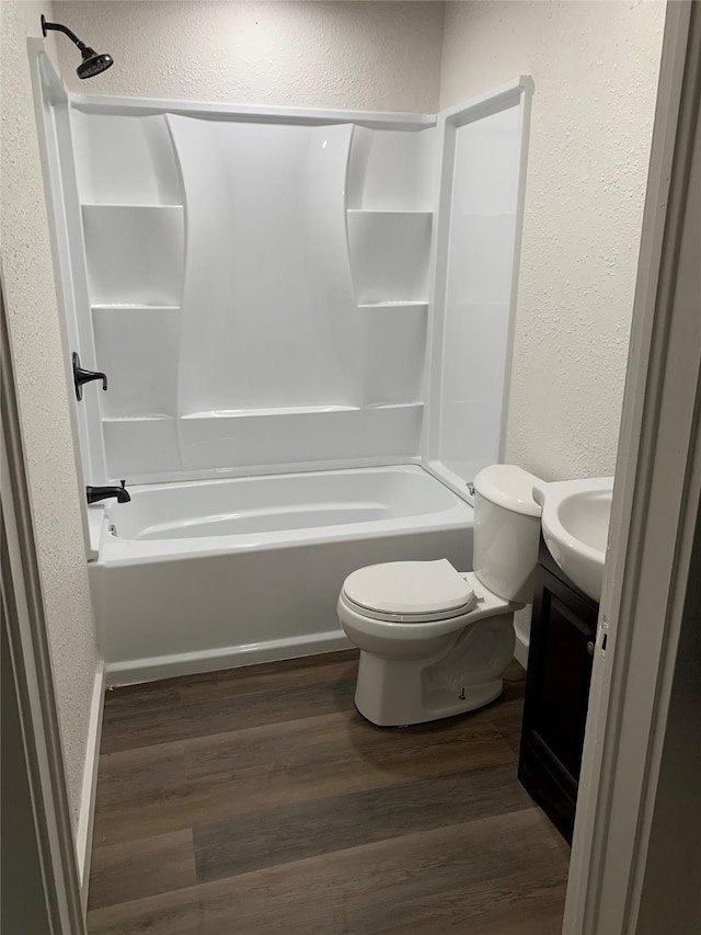 full bathroom with a textured wall,  shower combination, and wood finished floors