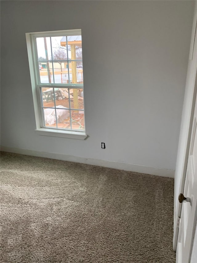carpeted spare room featuring baseboards