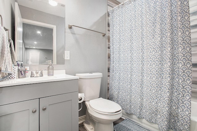 bathroom featuring toilet, vanity, and a textured wall