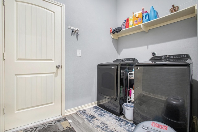 laundry room featuring washing machine and dryer, baseboards, and wood finished floors