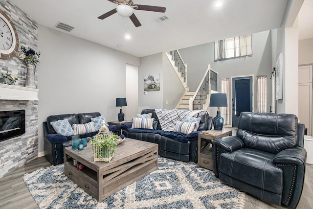 living area with ceiling fan, stairs, wood finished floors, a fireplace, and recessed lighting