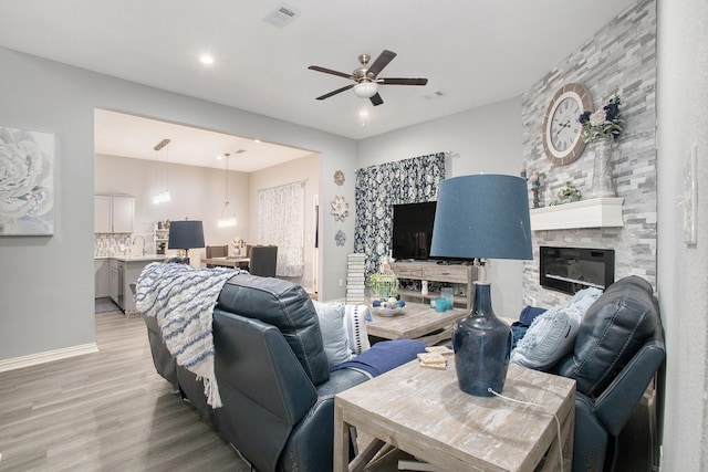 living area with a ceiling fan, light wood finished floors, a fireplace, and recessed lighting