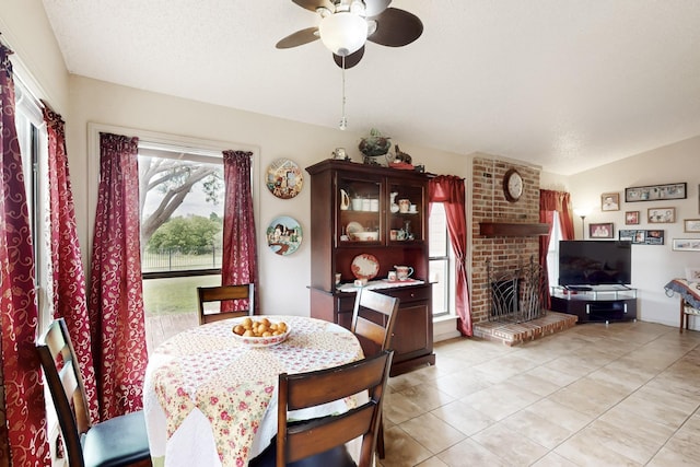 dining area with ceiling fan, light tile patterned floors, and a fireplace