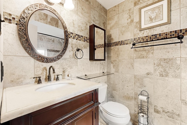 bathroom featuring toilet, tile walls, and vanity