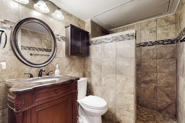 bathroom featuring a walk in shower, toilet, tile walls, and vanity
