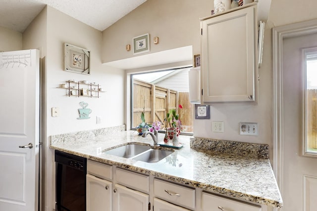 kitchen with a sink, black dishwasher, and light stone countertops