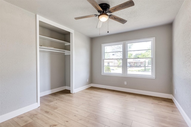 unfurnished bedroom featuring a textured ceiling, a textured wall, light wood-style flooring, and a closet