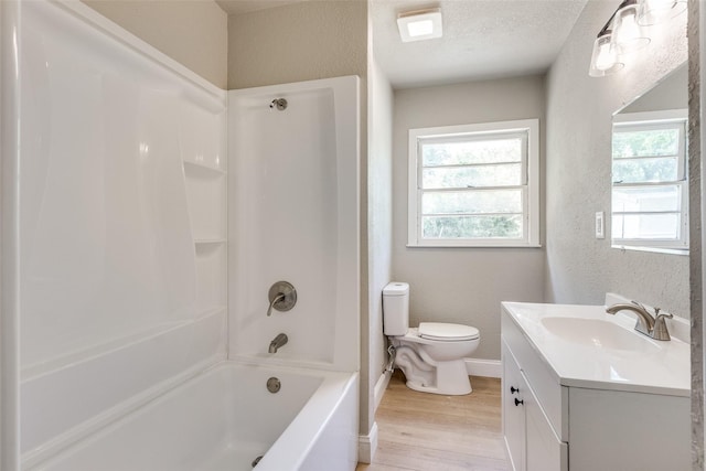 full bathroom with toilet, a textured wall, wood finished floors, and vanity