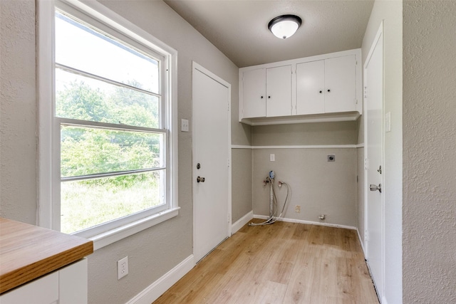 laundry area with cabinet space, electric dryer hookup, baseboards, and light wood finished floors