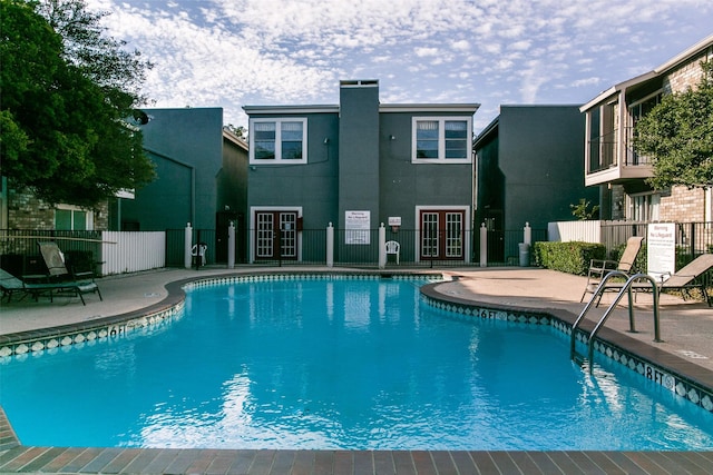pool featuring a patio, fence, and french doors