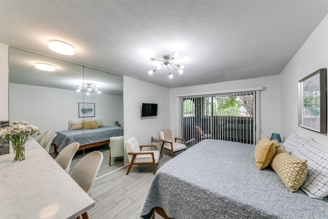 bedroom featuring a textured ceiling, a notable chandelier, and light wood-style floors