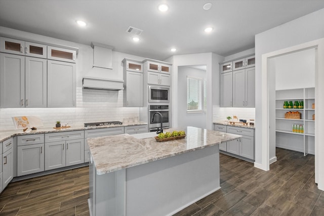 2812 Bluff Creek Dr, Mansfield, TX 76063 - kitchen with a kitchen island with sink, visible vents, custom exhaust hood, stainless steel appliances, and dark wood-type flooring