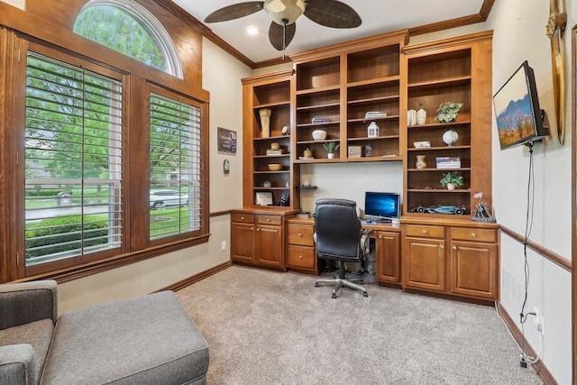 office featuring ceiling fan, crown molding, built in study area, baseboards, and light carpet