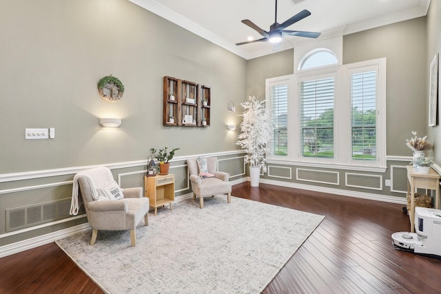 living area with a ceiling fan, visible vents, ornamental molding, and wood finished floors