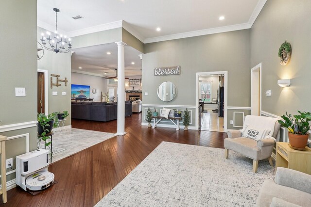 living room featuring ornamental molding, ornate columns, wood finished floors, and visible vents