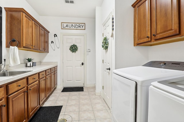 laundry area with visible vents, washing machine and dryer, light tile patterned flooring, a sink, and cabinet space