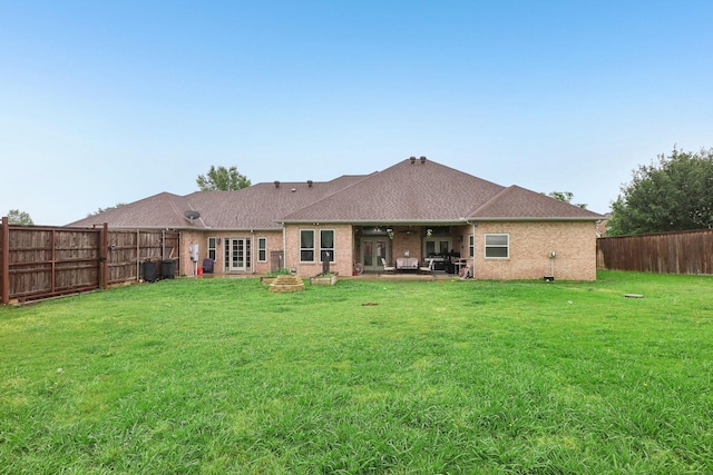 rear view of house with a lawn, a patio, a shingled roof, and a fenced backyard
