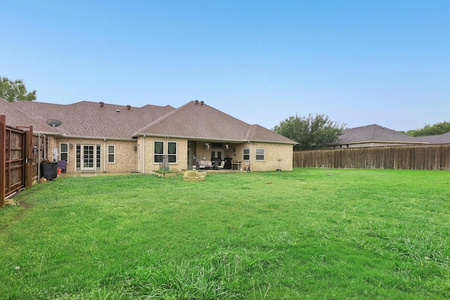rear view of property featuring a fenced backyard, a patio, a yard, and brick siding