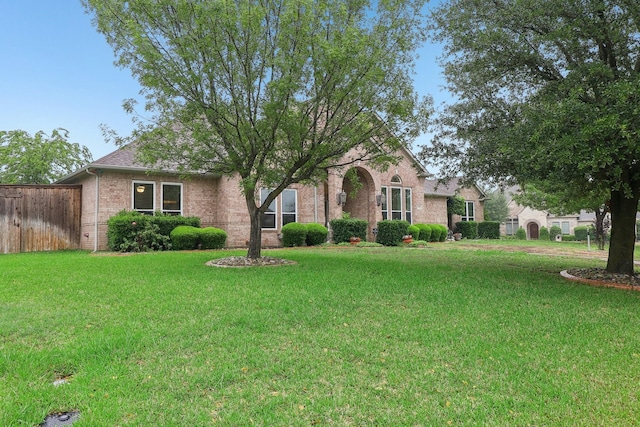 view of front of home featuring brick siding, fence, and a front yard