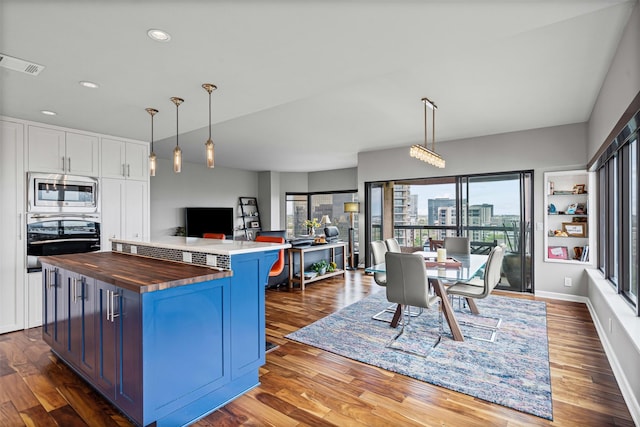 kitchen with appliances with stainless steel finishes, plenty of natural light, butcher block countertops, and visible vents