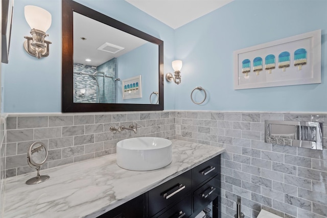 full bath with vanity, a wainscoted wall, tile walls, a shower stall, and visible vents