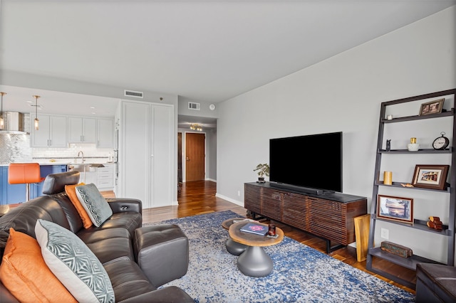 living area with visible vents, baseboards, and wood finished floors
