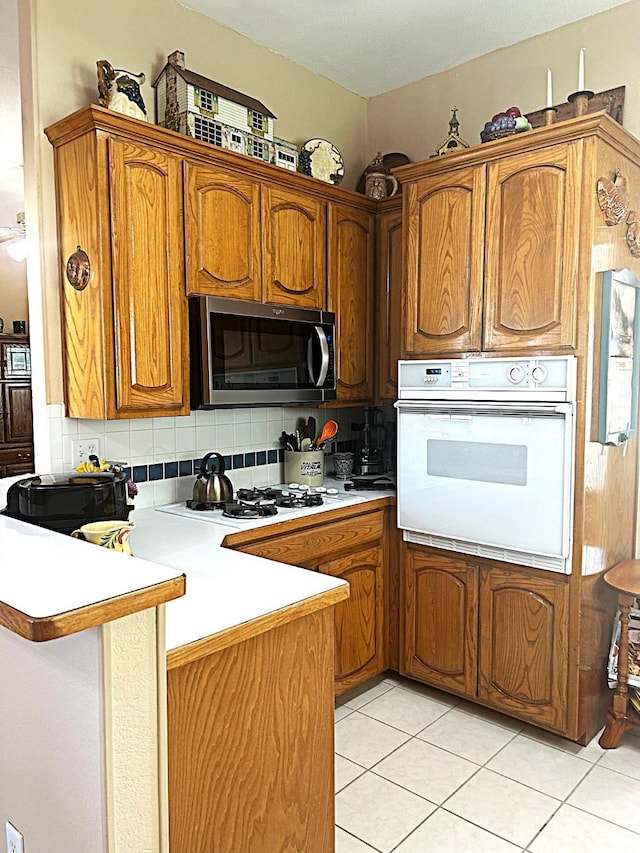 1561 Waterford Dr, Lewisville, TX 75077 - kitchen featuring white appliances, a peninsula, light countertops, brown cabinetry, and light tile patterned flooring