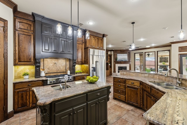 kitchen featuring a sink, a kitchen island with sink, a ceiling fan, stainless steel built in fridge, and tasteful backsplash
