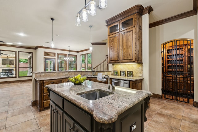 kitchen featuring a sink, a peninsula, a center island with sink, and ornamental molding