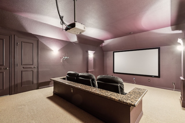 carpeted cinema room featuring a textured ceiling, a textured wall, baseboards, and lofted ceiling