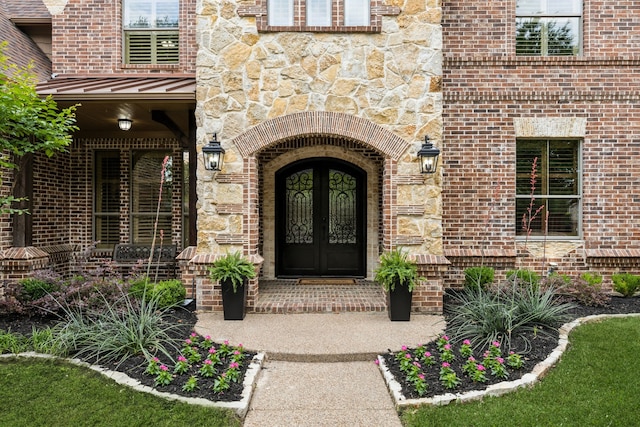 view of exterior entry with a standing seam roof, brick siding, and stone siding
