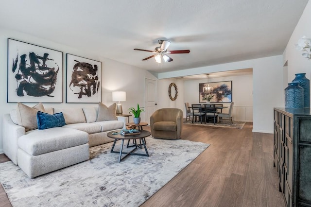 living area featuring baseboards, ceiling fan with notable chandelier, and wood finished floors