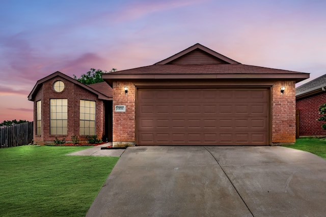 ranch-style home featuring a lawn, brick siding, driveway, and a garage