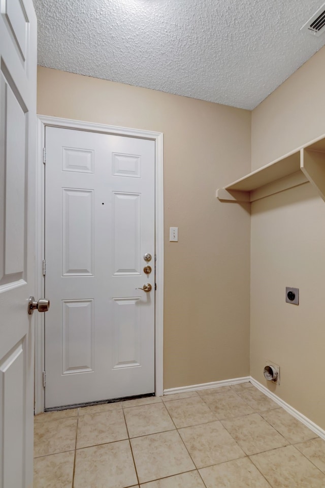 washroom with laundry area, a textured ceiling, electric dryer hookup, light tile patterned floors, and visible vents