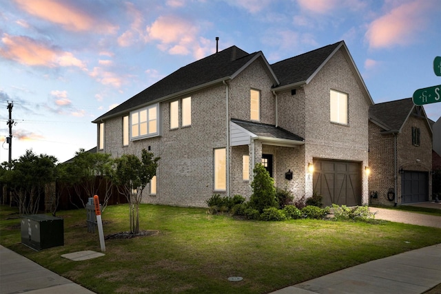 view of front facade featuring an attached garage, driveway, a front lawn, and brick siding