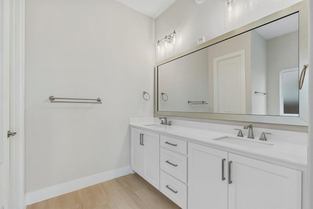 full bathroom featuring a sink, baseboards, and double vanity