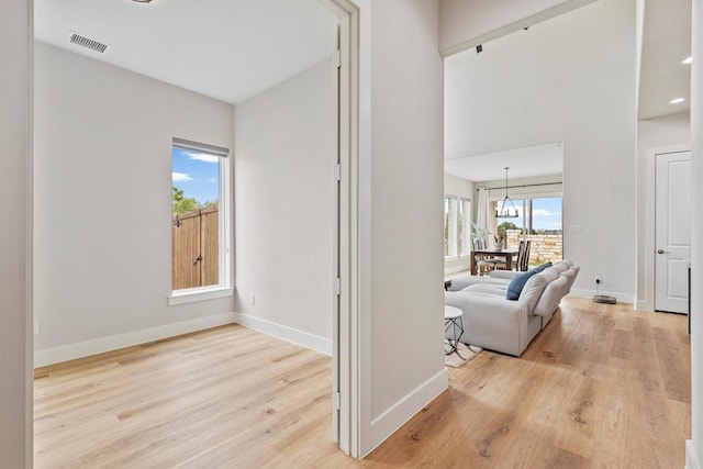 hall with baseboards, visible vents, and light wood finished floors