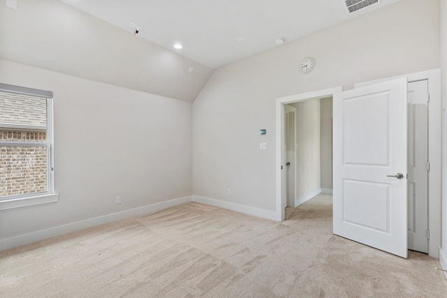 empty room with baseboards, visible vents, light carpet, and lofted ceiling