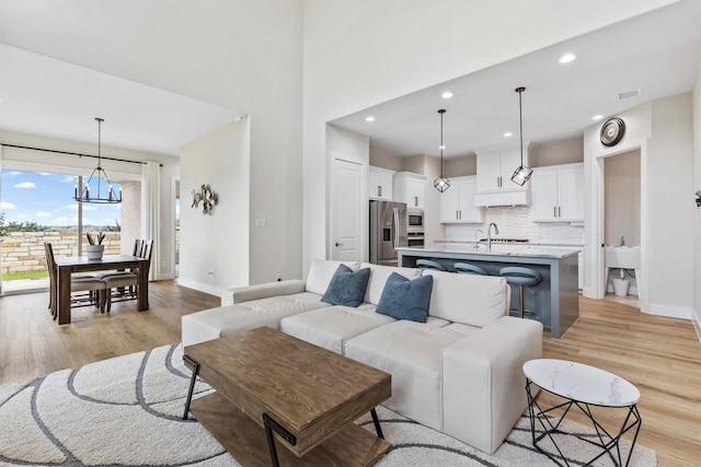 living area featuring recessed lighting, baseboards, a chandelier, and light wood-type flooring