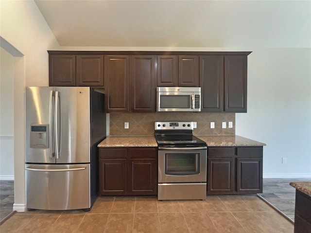 kitchen with light stone counters, appliances with stainless steel finishes, and dark brown cabinets