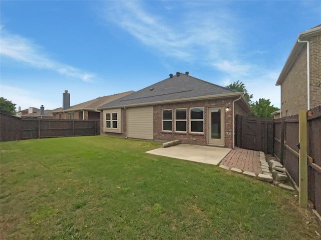 back of property with a fenced backyard, a patio, a lawn, and brick siding