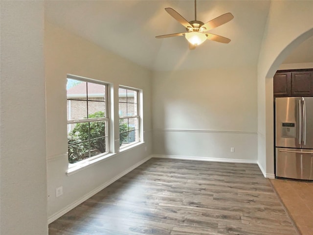 unfurnished room with arched walkways, ceiling fan, baseboards, and light wood-type flooring