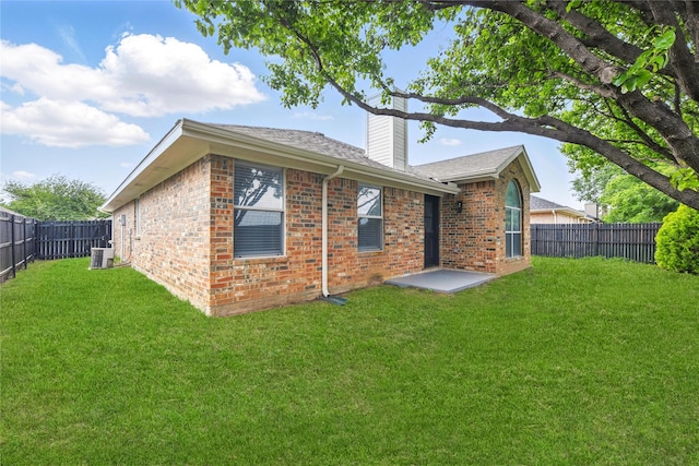 rear view of house with brick siding, cooling unit, and a fenced backyard