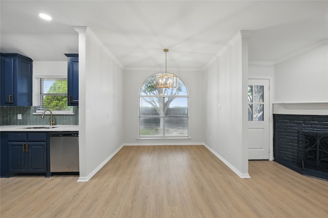 unfurnished dining area featuring crown molding, baseboards, a sink, and light wood-style floors